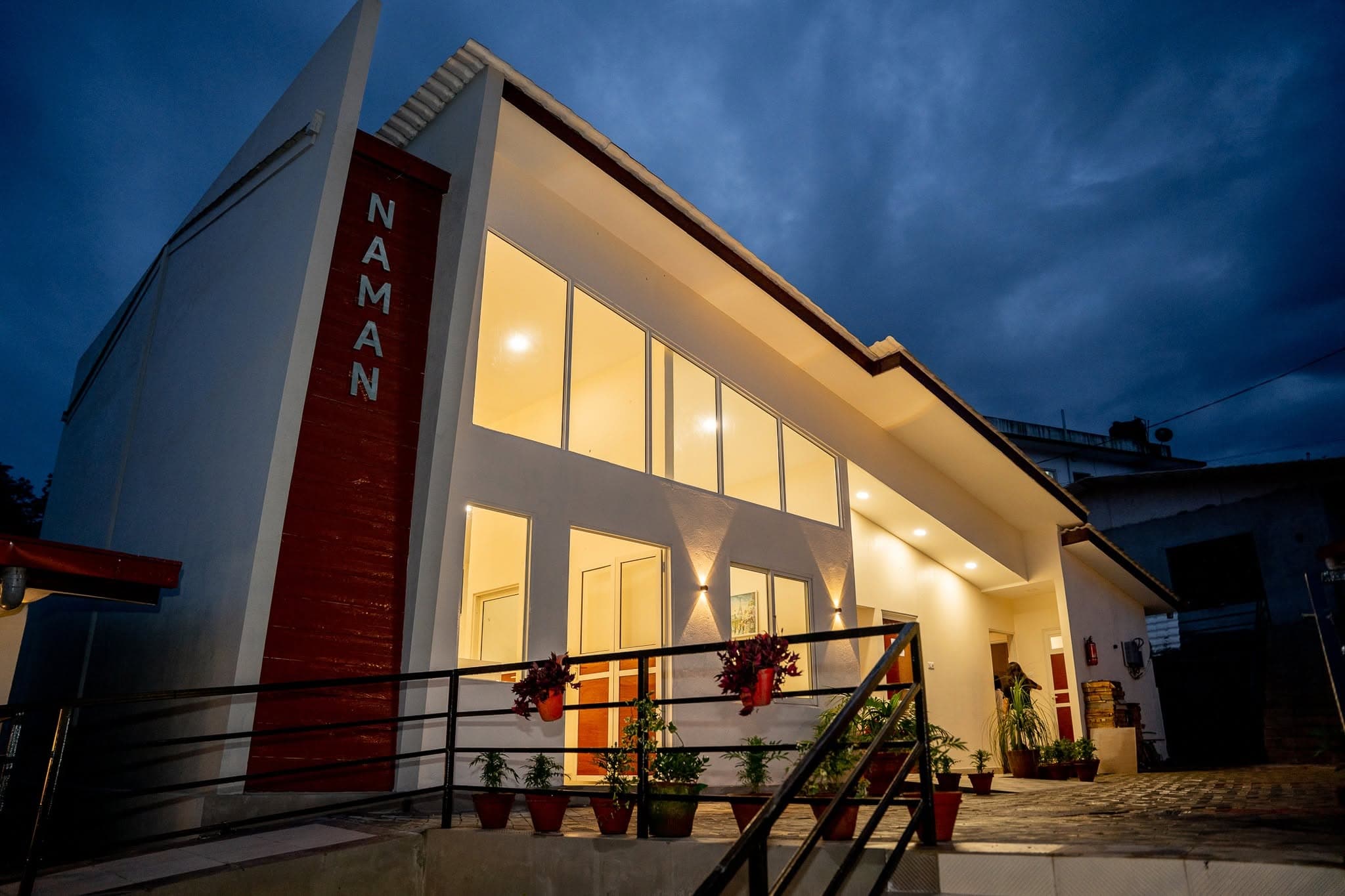 The Naman Care Home Bansbari branch at blue hour with the illuminated red NAMAN column